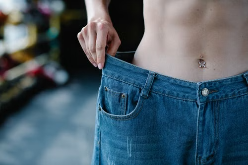 Person holding out loose-fitting jeans at the waist