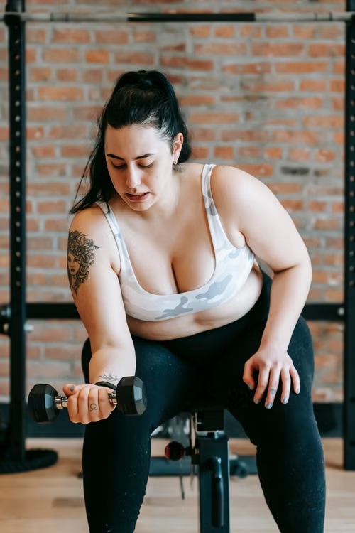 Woman training with a dumbbell on a gym bench